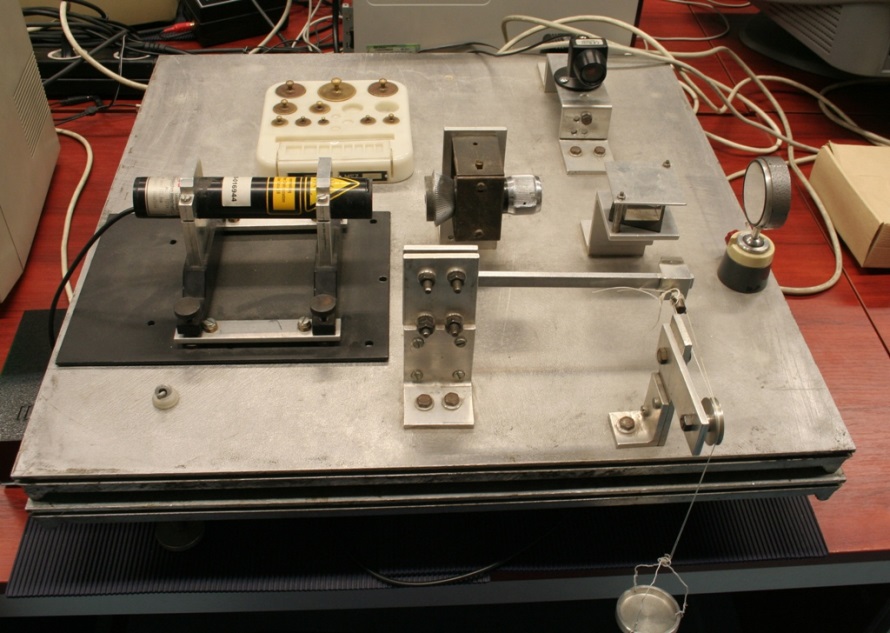 A rugalmassági modulus meghatározására szolgáló mérési elrendezés, baloldalt látható a He-Ne gázlézer, ami a koherens hullámok forrása, mellette a lézernyalábtágító távcső